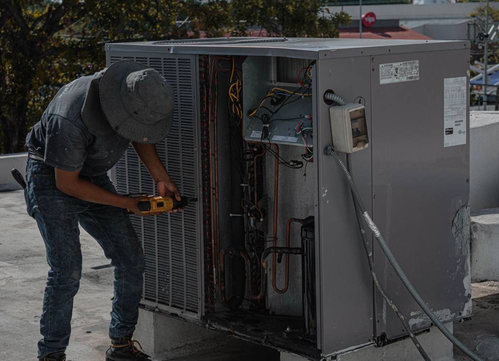 Technician working on a rooftop heating and cooling unit